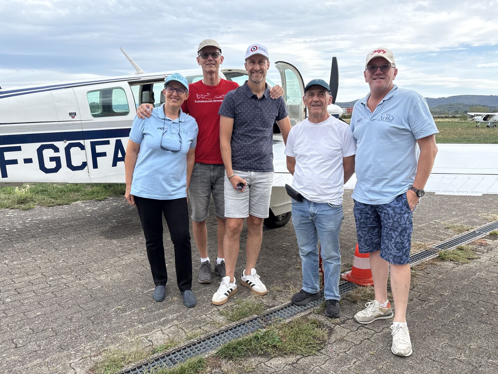Gäste eines französischen Aéroclubs mit Mitgliedern der Fliegergruppe vor einer Beechcraft Bonanza